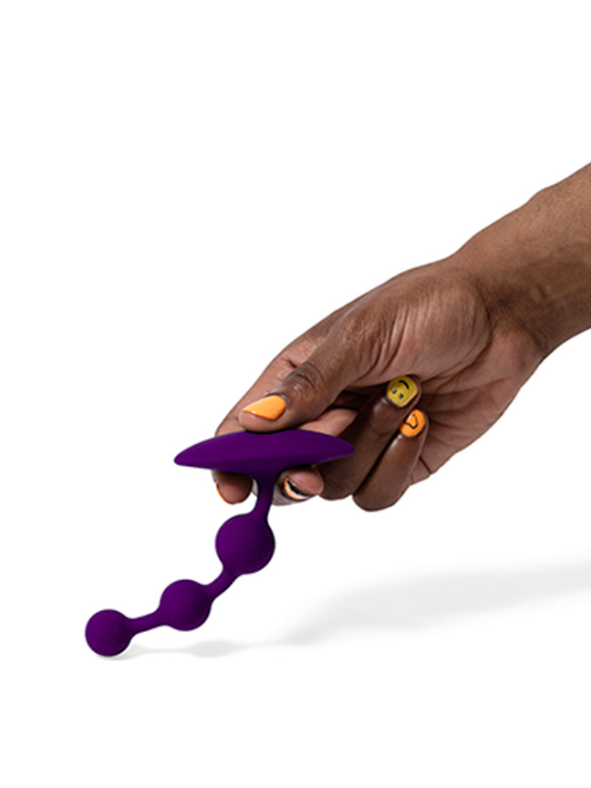 a hand holding purple anal beads