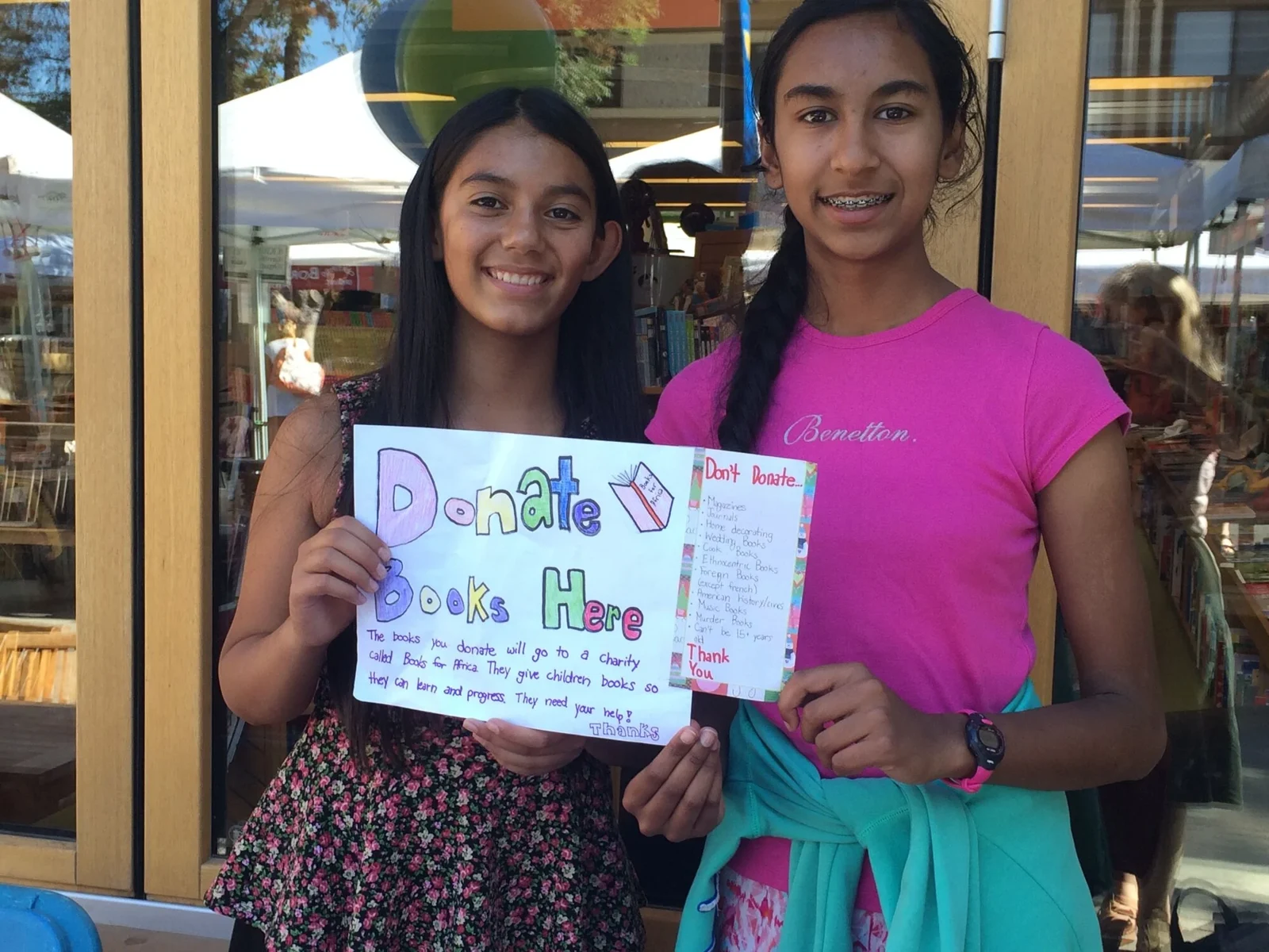 Two young readers with a handmade book donation sign