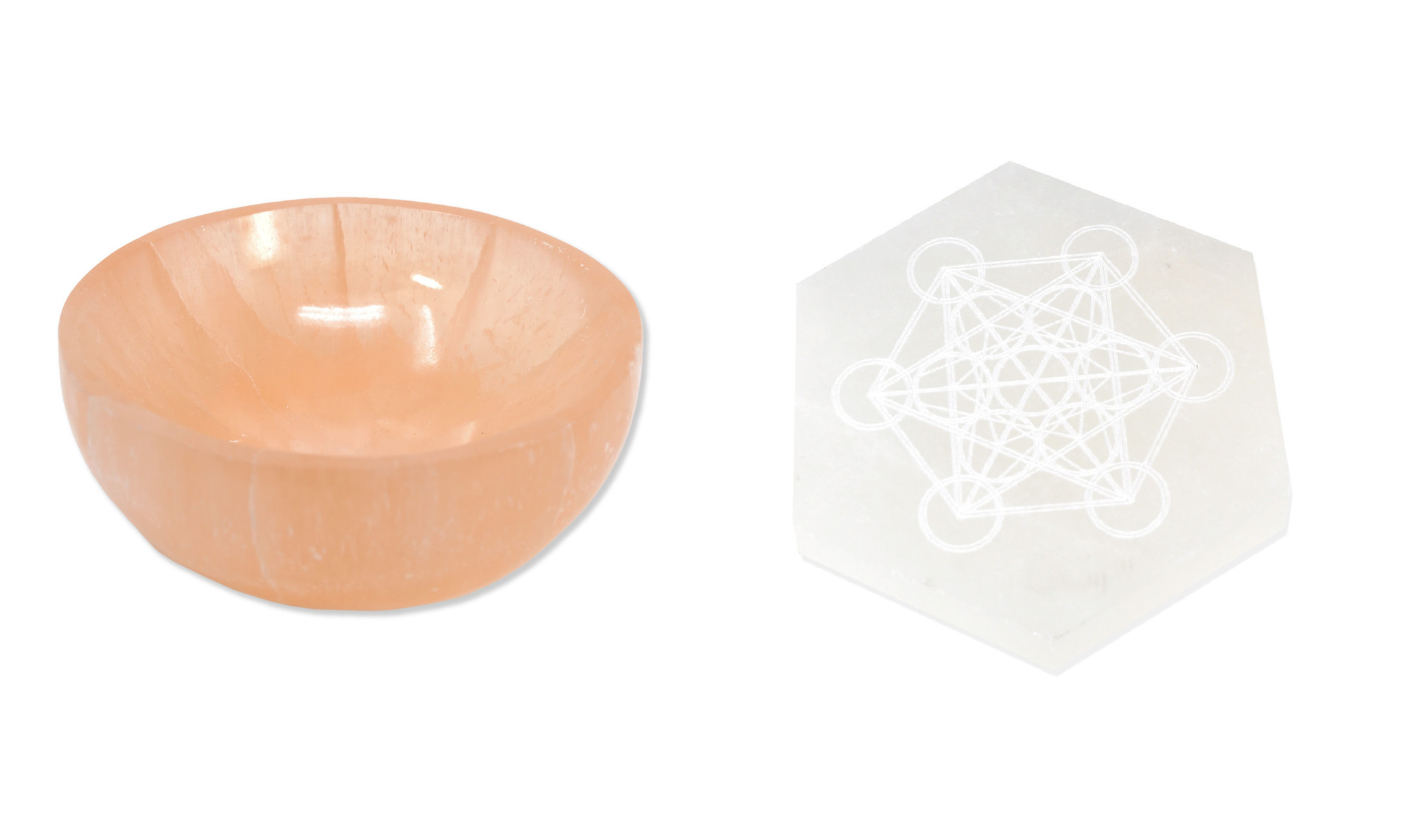 Peachy colored Selenite bowl, about 3 inches in diameter next to a white colored selenite piece engraved with a metatron cube pattern etched into it.