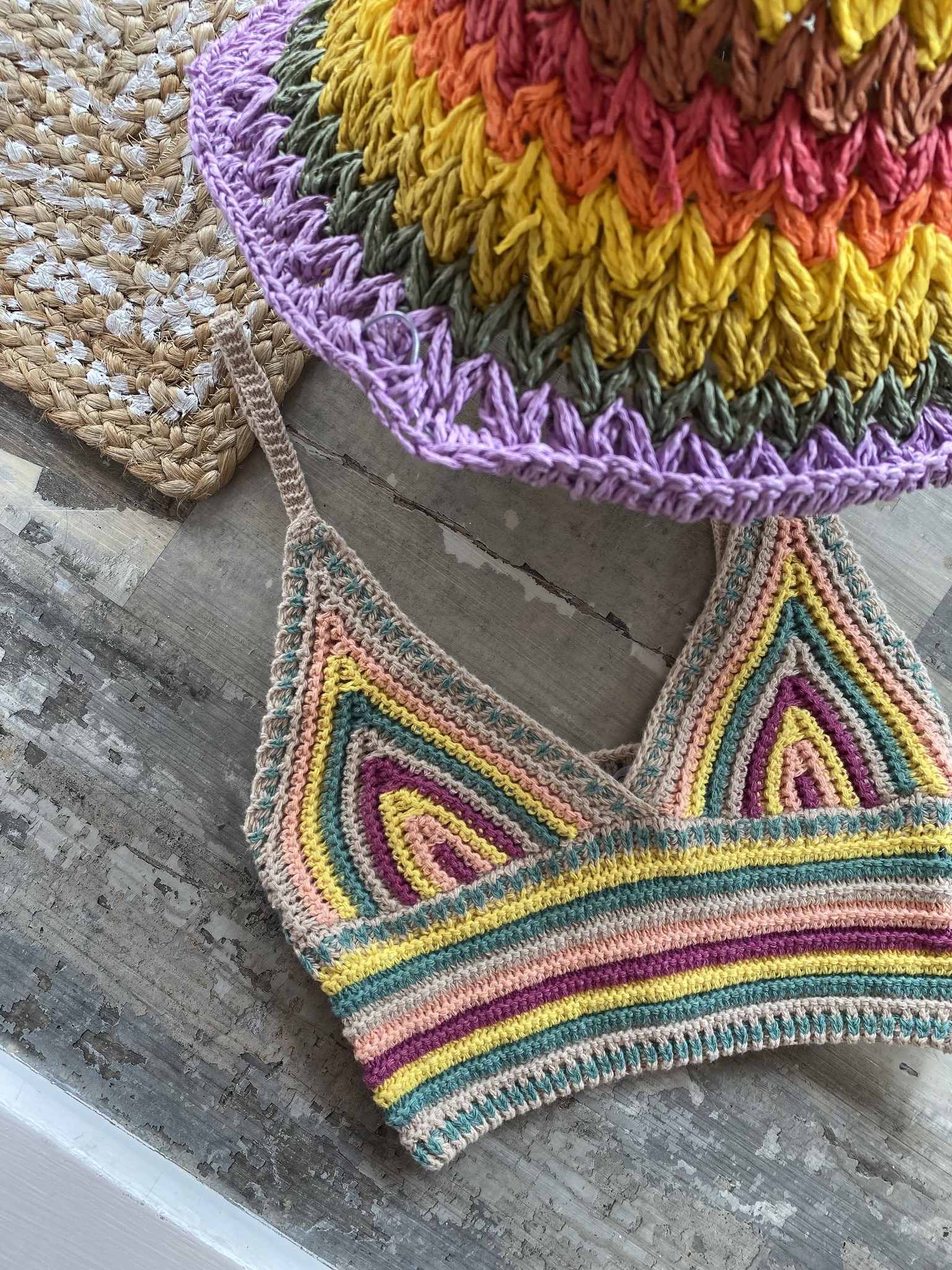 Colorful crochet bralette and hat featured againt gray marbled background