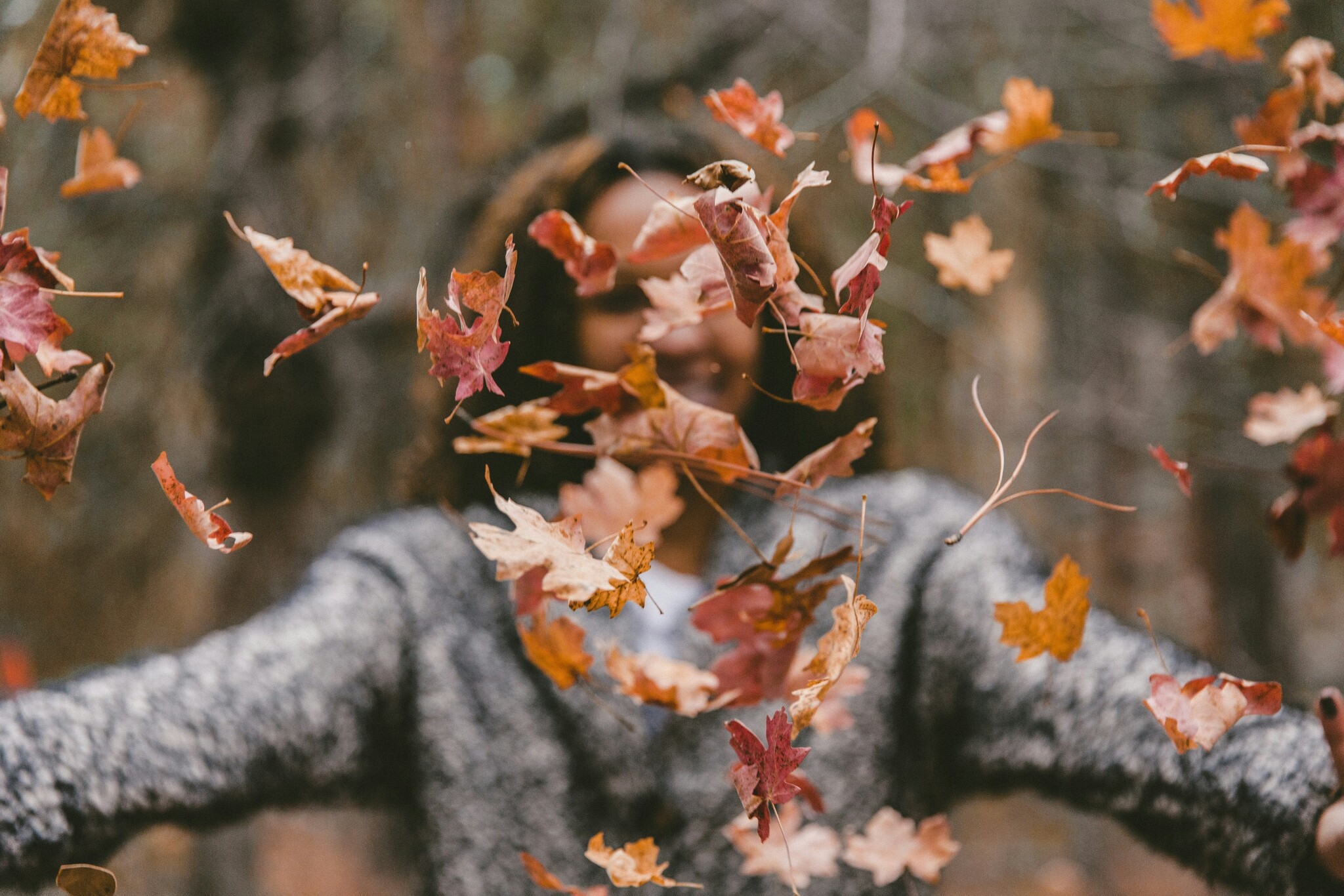 Woman happily throwing leaves. Photo by Jakob Owens on Unsplash