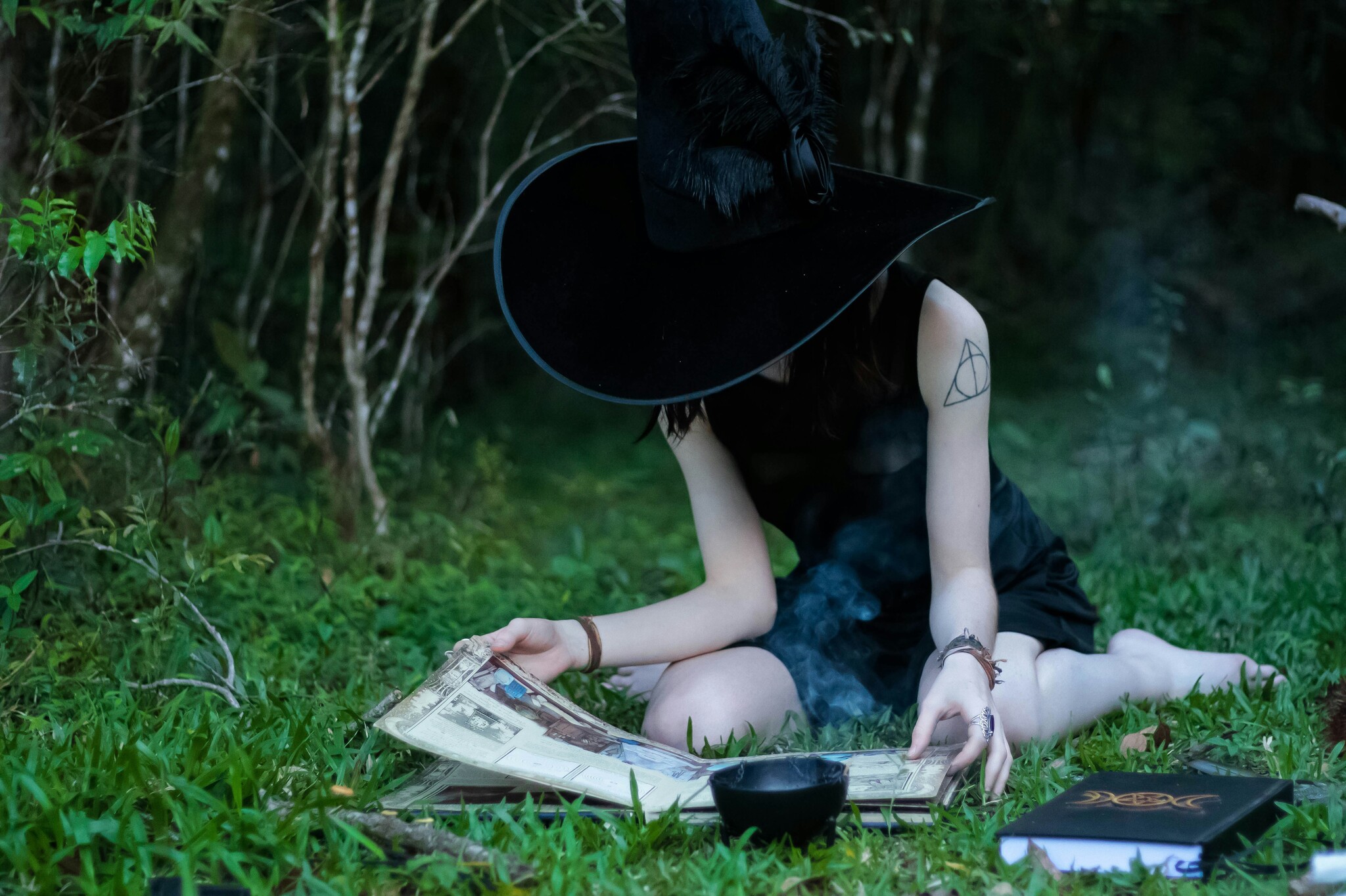 Witchy person sitting in the woods reading. Photo by Halanna Halila on Unsplash