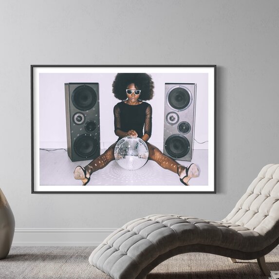 Framed Print on Rag Paper: African woman in black dress and sunglasses holding disco ball by Vladimir Vladimirov via Getty Images Gallery