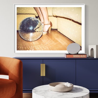 Framed Print on Rag Paper Young woman wearing high heels standing by disco ball on floor in party by Westend61 via Getty Images Gallery