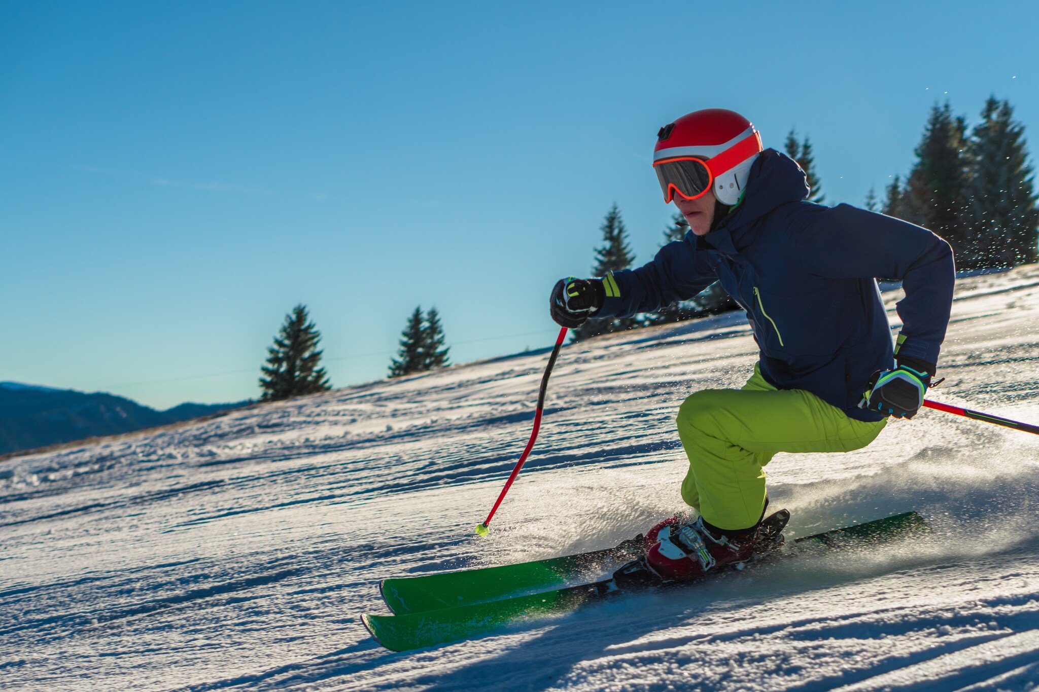Male skier in green pants and orange helmet