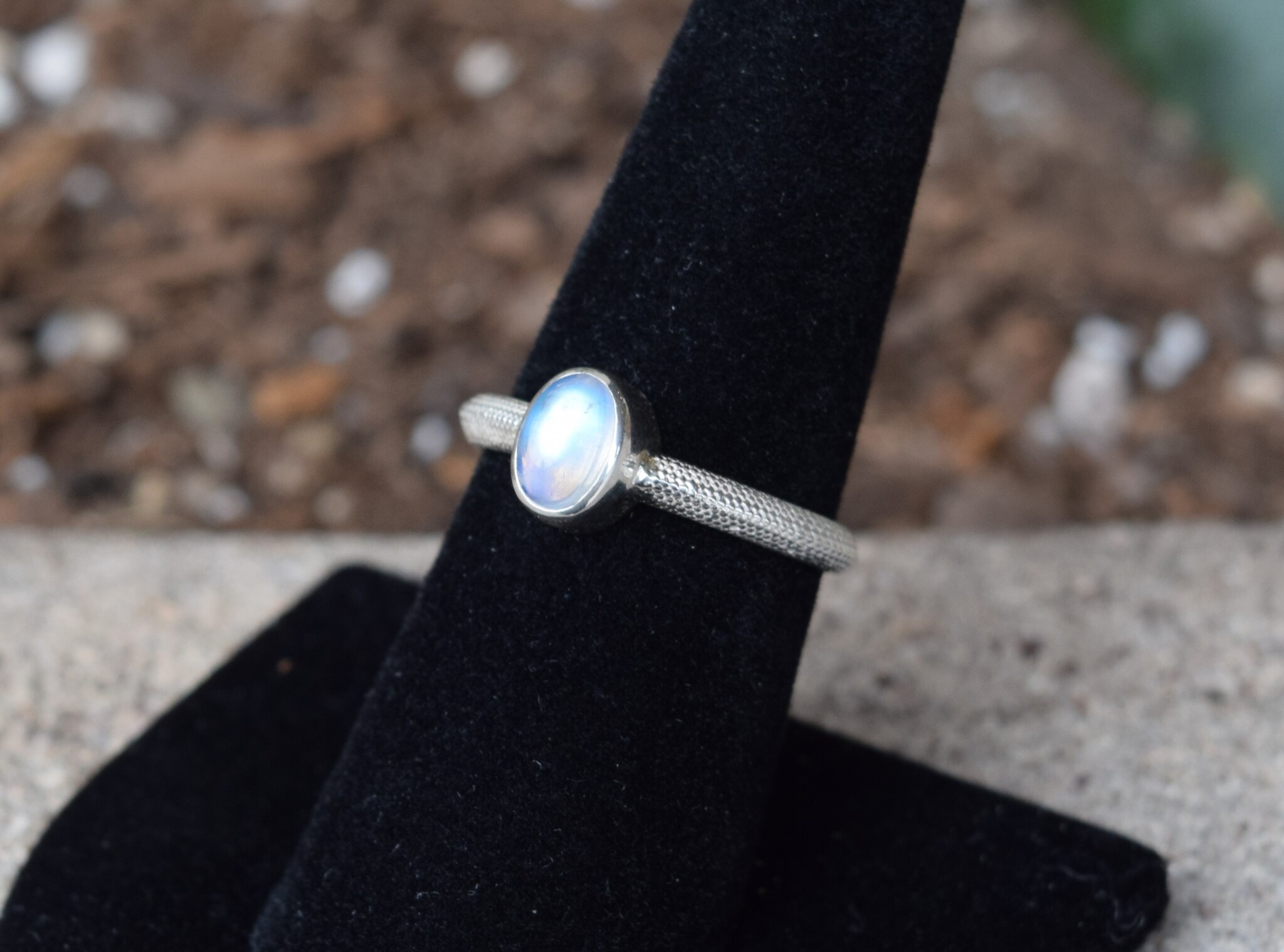 STB 001 SS Rainbow Moonstone 7mm Oval, Bezel Set Textured Snake Band, Ring Size 7