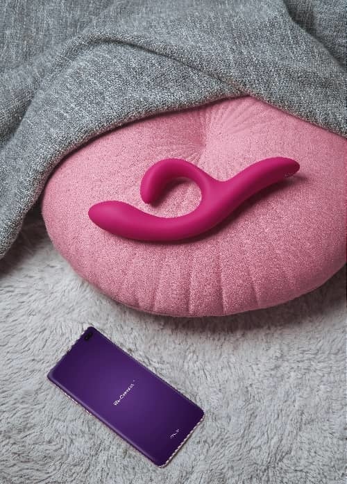 We-Vibe Nova 2 - Mood Shot of Nova 2 on throw pillow next to smartphone with We-Connect app loading screen