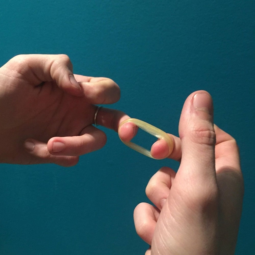 The condom's tip now removed, it is rolled up and looks like a small ring.