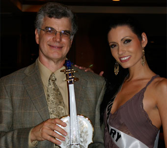 Tom Metzler receives a hand-painted porcelain violin from Adrienn Bende, Miss Hungary, at a charity silent auction at the 2006 'Miss Universe' competition.