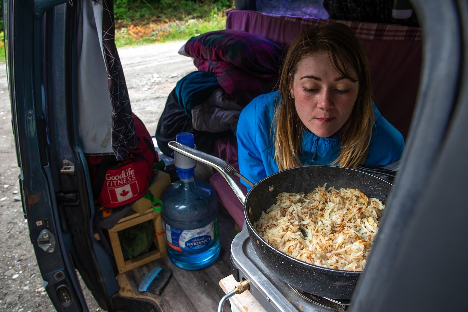 woman cooking dinner at the back of her van