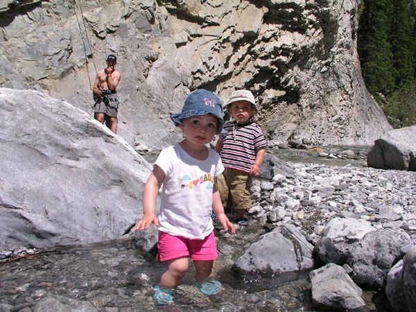 Toddlers playing in the creek with adults climbing in the back