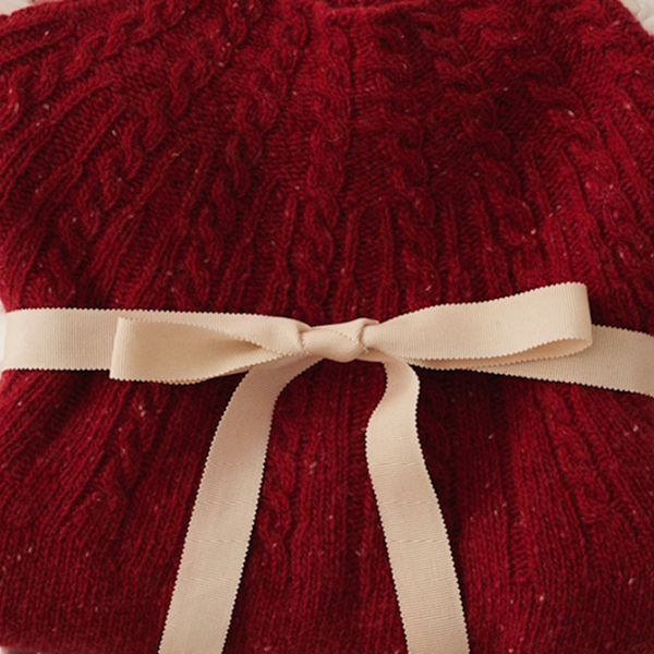 Un pull rouge avec un nœud noué autour, adapté pour un enfant en hiver.