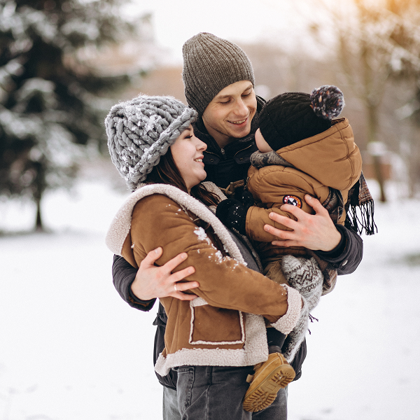 Un homme et une femme enlacent leurs deux enfants dans la neige, tous vêtus de tenues assorties.