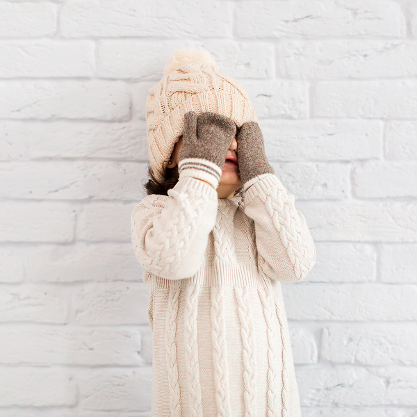 Une petite fille portant un pull et un chapeau, vêtue pour les fêtes de Noël 2025.
