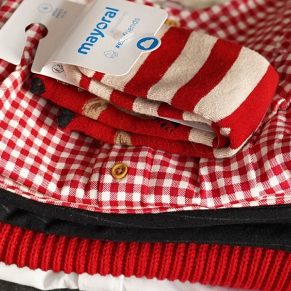 Une pile de chaussettes rayées rouges et blanches avec une chemise assortie, pour les tenues de réveillon enfants 2025.
