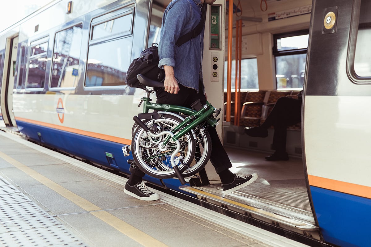 Person boarding a train with a folded bicycle