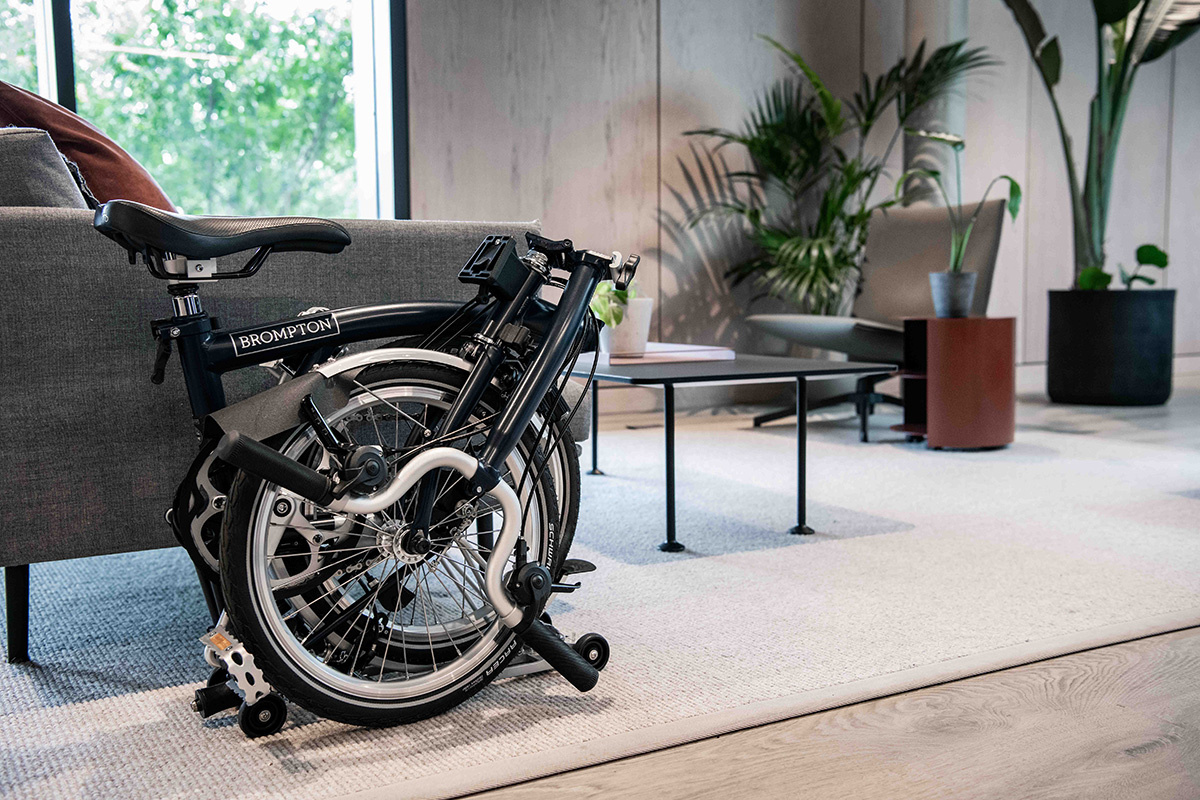 A folded bicycle sitting next to a sofa