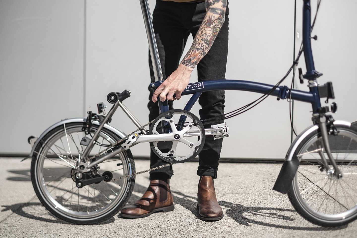 Person undoing the locking mechanism at the rear of a Brompton bike