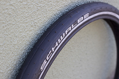 Black, treadless tire with white Schwalbe logo leaning up against a wall