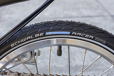 Close-up of a black tire with a light blue and grayish white Schwalbe Marathon Racer logo on the sidewall