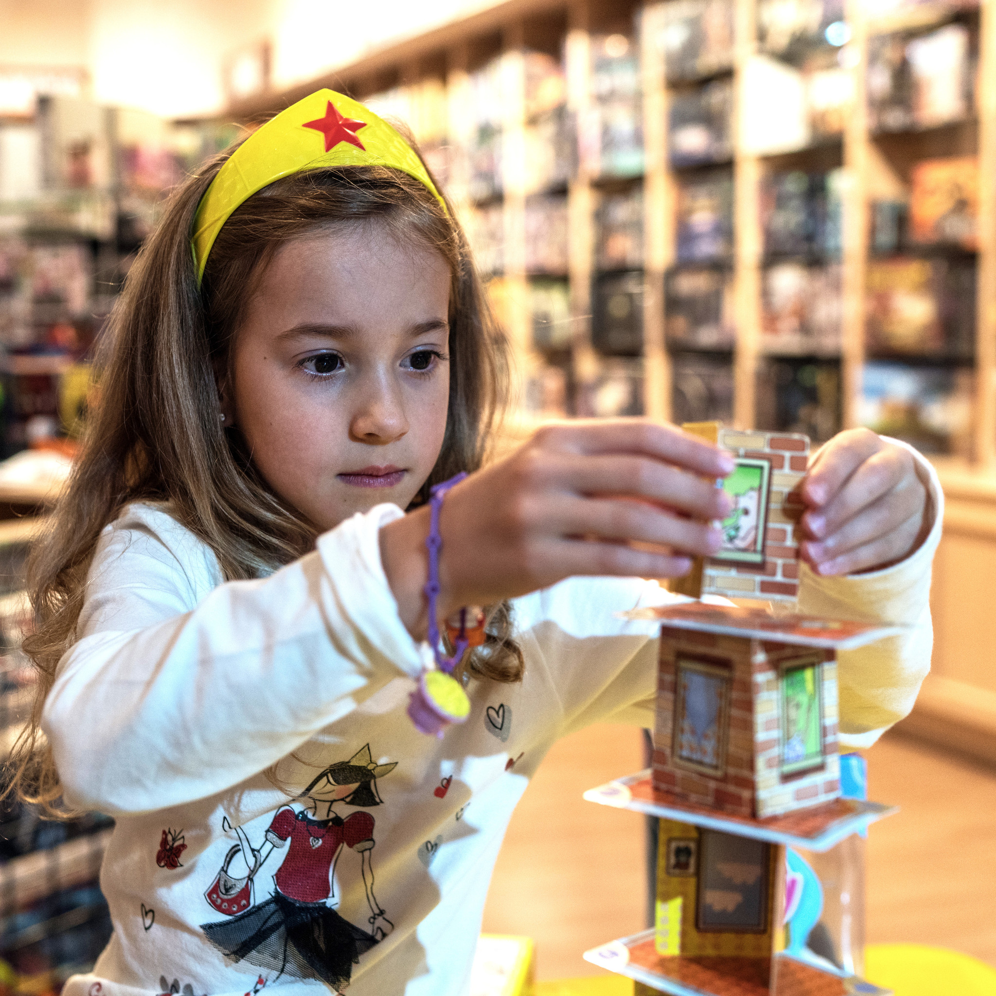 A young girl playing a game of Rhino Hero inside Rain City Games