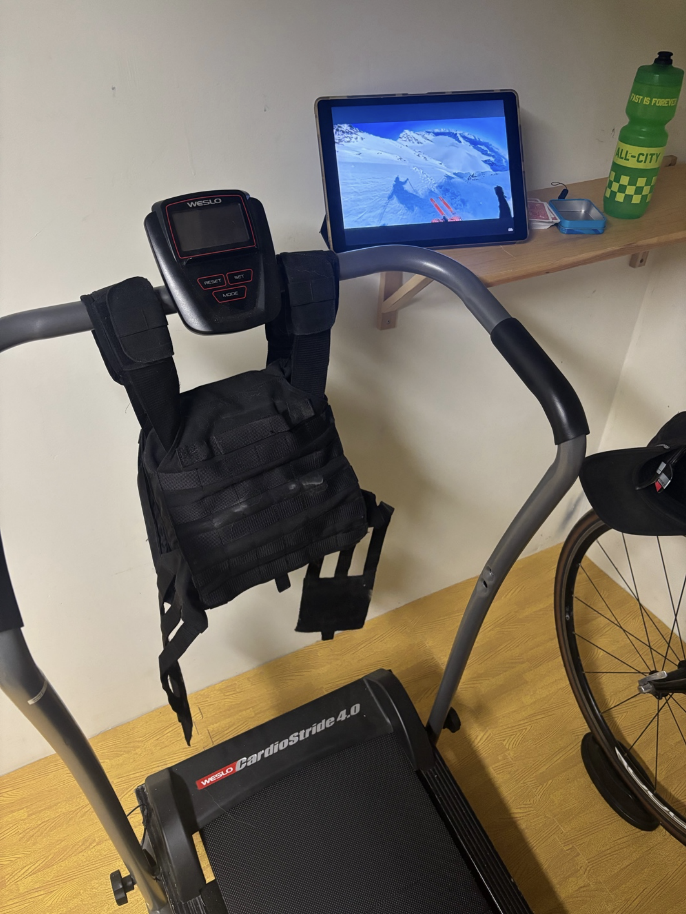 Home treadmill with a weighted vest and ski movie in the background