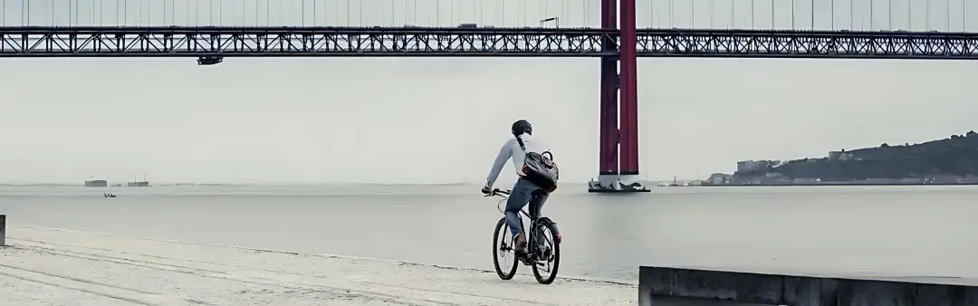 Cycliste de vélo électrique cyclotourisme roulant au bord d'un fleuve vers un pont.