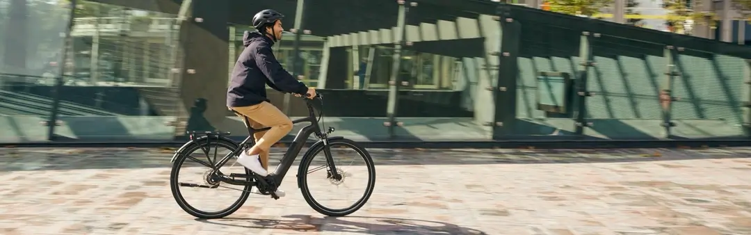 Cycliste roulant sur un vélo électrique de bonne taille en ville.