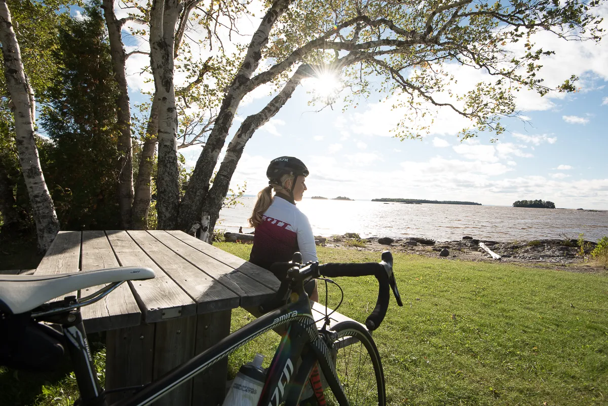 Femme cycliste se reposant regardant le lac du lac St-Jean après un tour du lac St-Jean réussi.