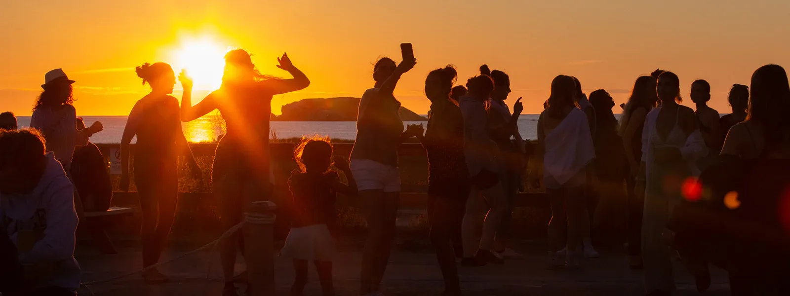 Vue extérieure de la microbrasserie À l’abri de la Tempête aux Îles-de-la-Madeleine, avec des gens profitant du coucher de soleil en bord de mer.