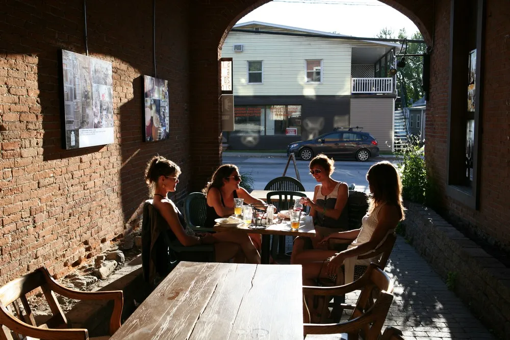 Façade de la Brasserie Dunham à Dunham, avec terrasse conviviale en bois surplombant la rivière et vue sur la nature.