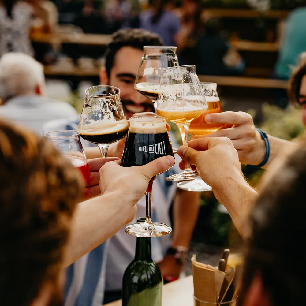 Groupe d’amis trinquant avec des bières variées à l’extérieur de la microbrasserie Dieu du Ciel! à Saint-Jérôme.