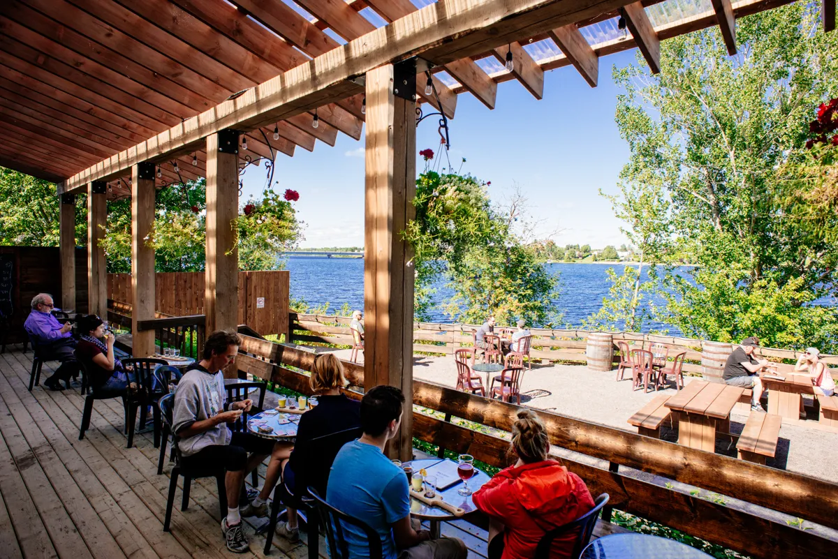 Vue extérieure de la microbrasserie La Chouape à Saint-Félicien, sur fond de terrasse en bois donnant sur la rivière et la végétation.