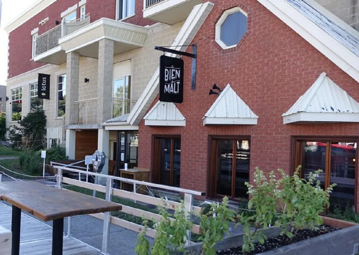 Groupe de femmes assises à l’ombre dans la cour intérieure du Bien, le Malt à Rimouski, partageant une bière après une balade à vélo.