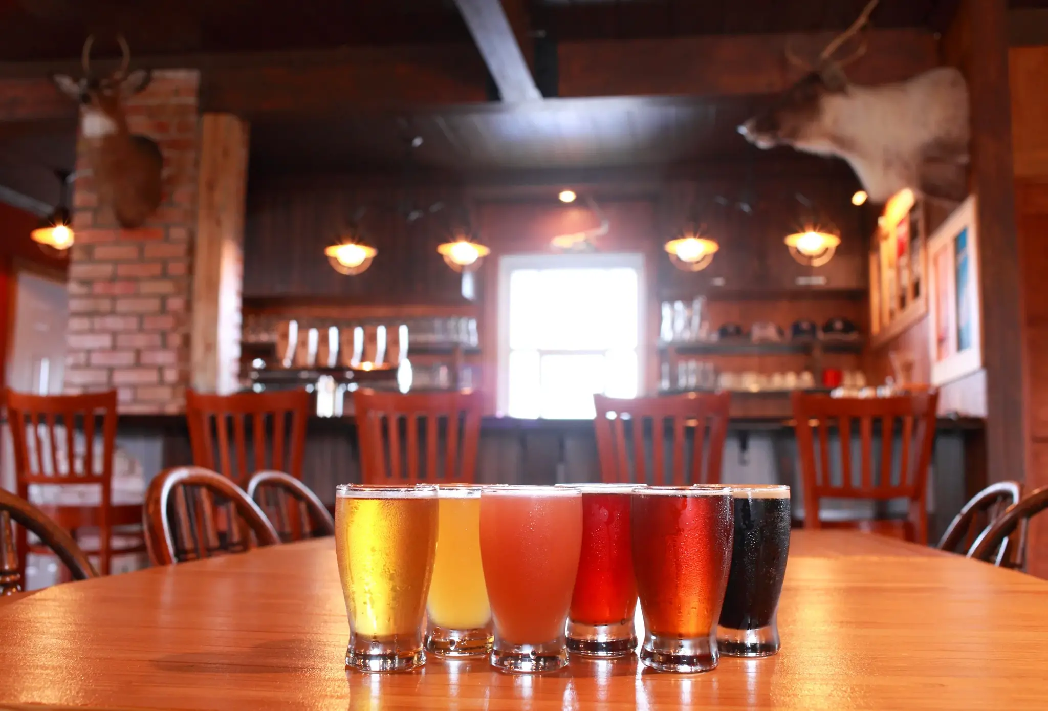 Table de dégustation avec six verres de bières colorées dans l’intérieur rustique de la microbrasserie Le Coureur des Bois à Dolbeau-Mistassini.