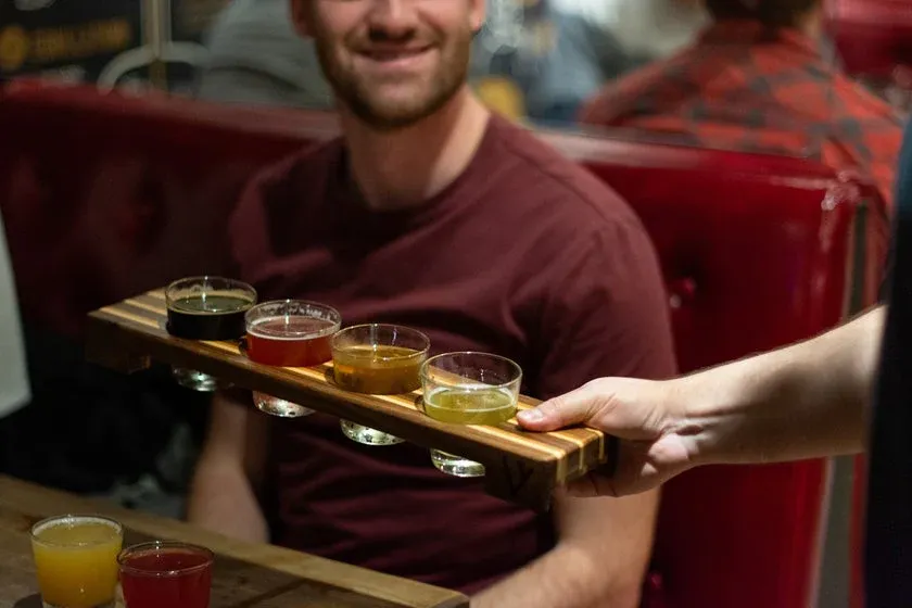 Enseigne noire distinctive du Trèfle Noir à Rouyn-Noranda accrochée sur la façade de brique rouge de la microbrasserie.