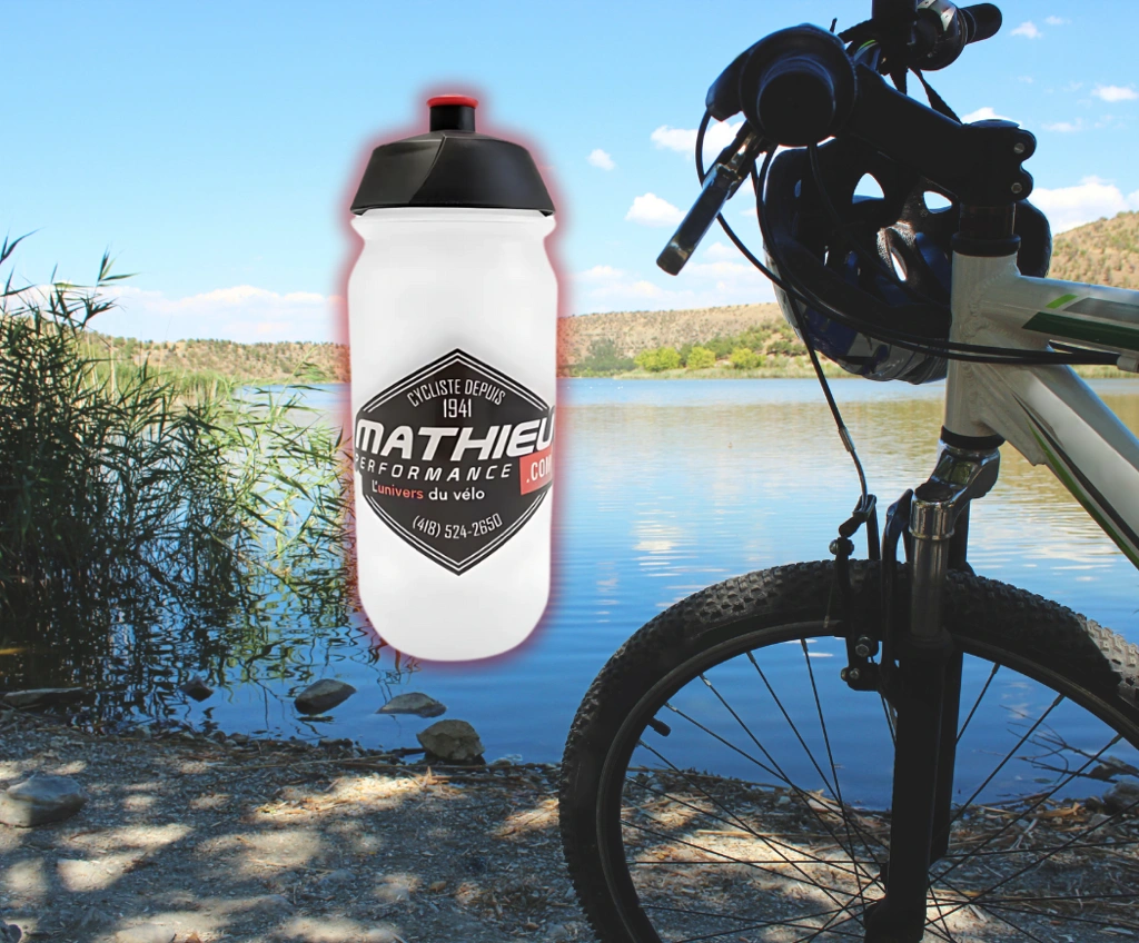 Bouteille d’eau Mathieu Performance fixée au cadre d’un vélo de montagne en bordure de lac, idéale pour l’hydratation en randonnée.