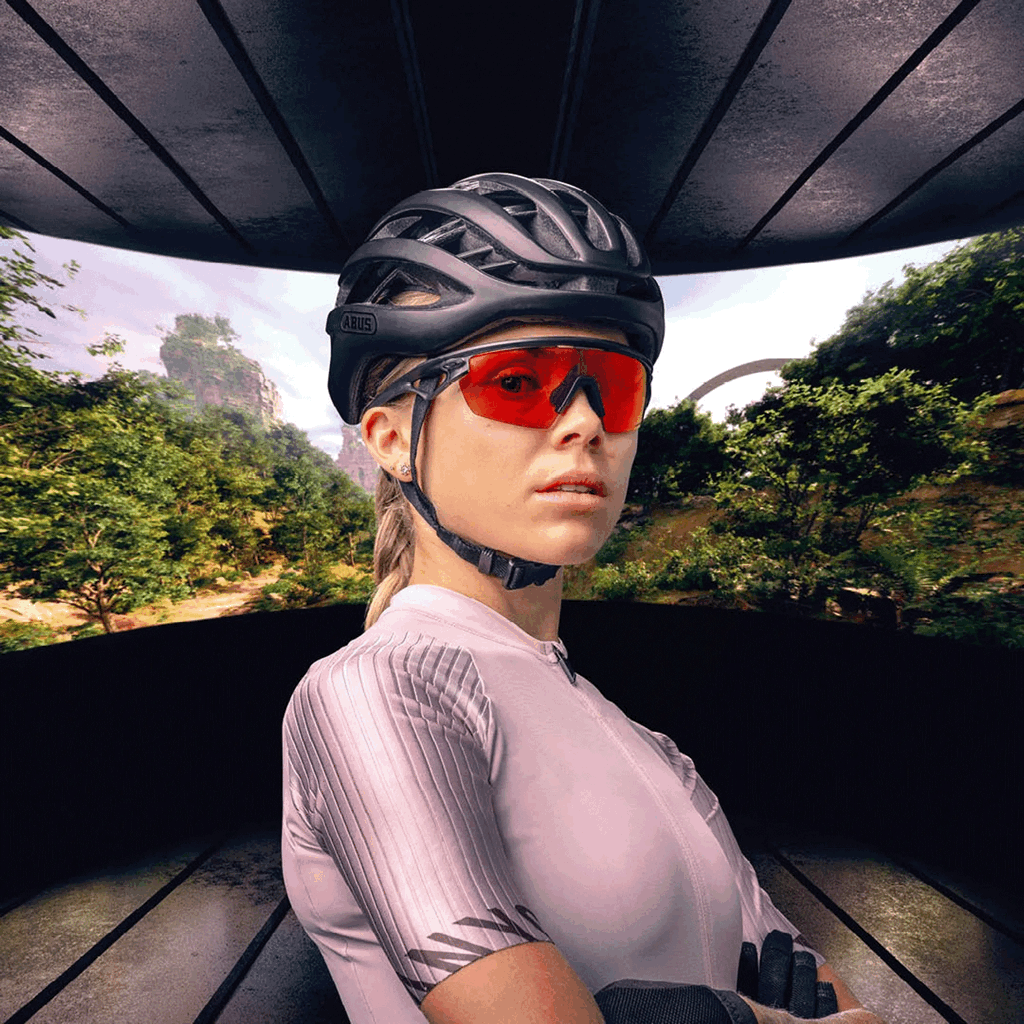 Cycliste équipée d’un casque Abus et de lunettes de protection UV rouges, idéale pour rouler en toute visibilité et sécurité.