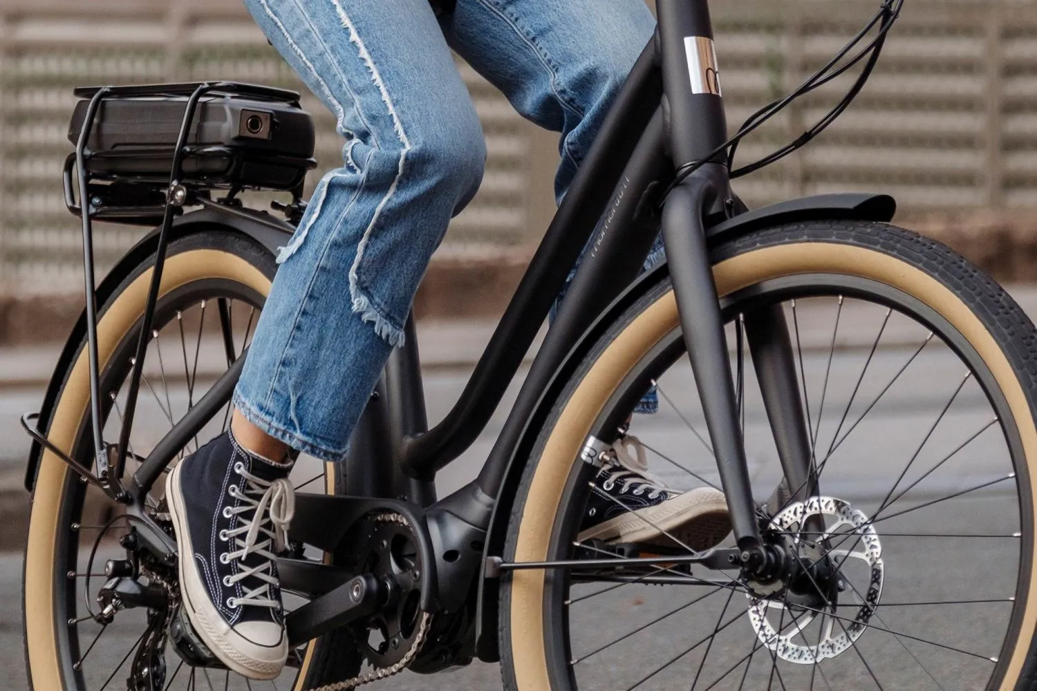 Vue rapprochée d’un vélo électrique noir utilisé par une personne en jeans et espadrilles Converse, illustrant les trajets quotidiens urbains au Québec.