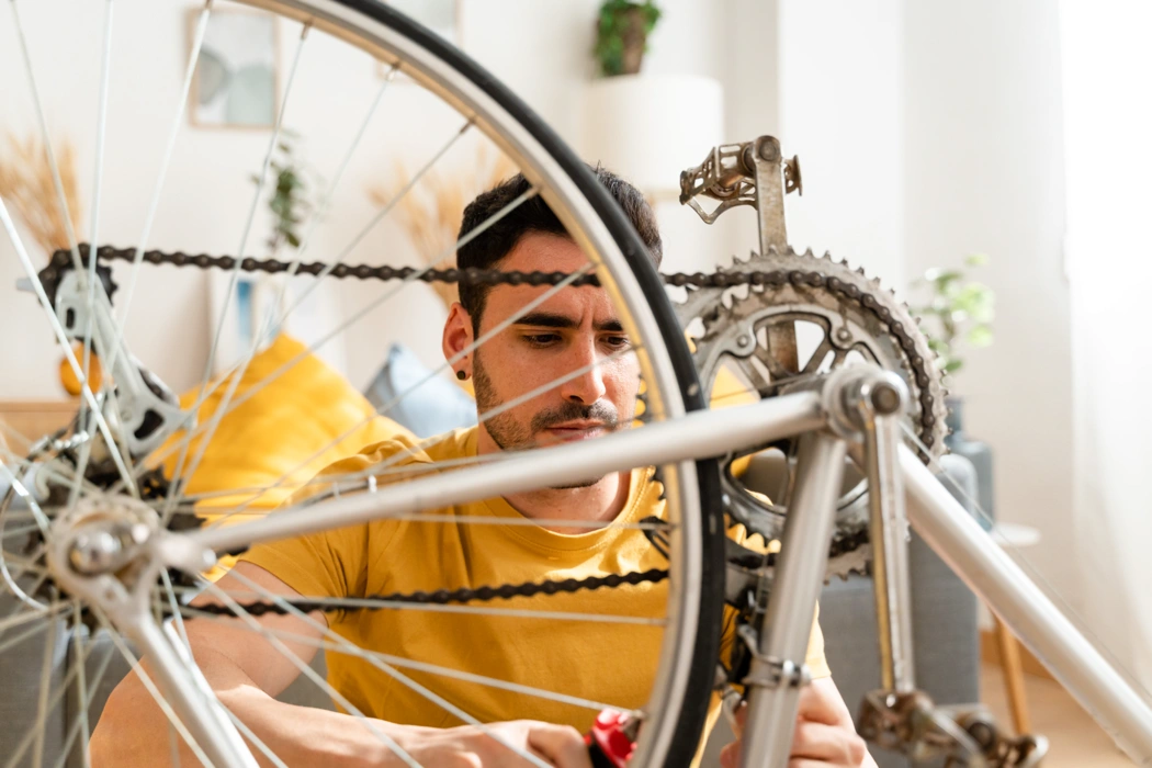 Mécanicien qui entretient la transmission d’un vélo, illustrant une efficacité mécanique réduite et le besoin d’un bon réglage.