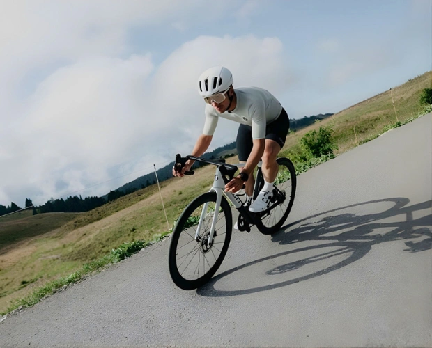 Cycliste sur route en position aérodynamique, illustrant l’importance d’une position sur le vélo bien ajustée pour mieux rouler longtemps.