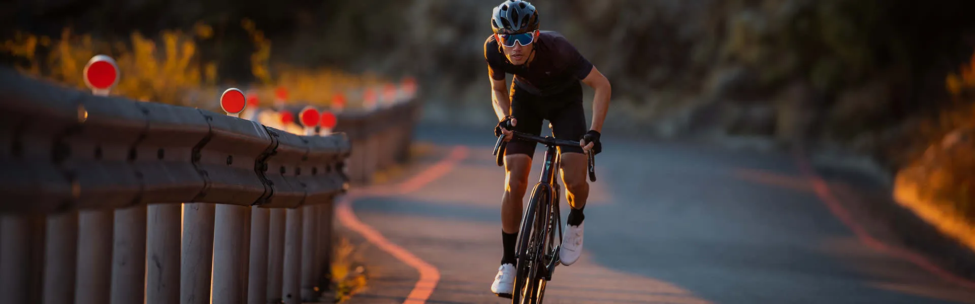 Cycliste qui force en montée sur une route au coucher du soleil, illustrant les problèmes observés souvent par les mécaniciens.