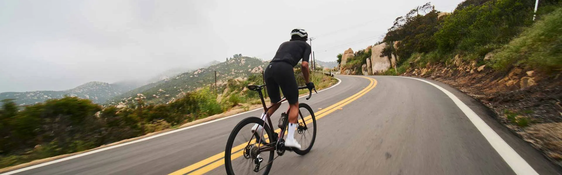 Cycliste de route qui monte une côte en virage, illustrant des techniques pour mieux grimper à vélo.