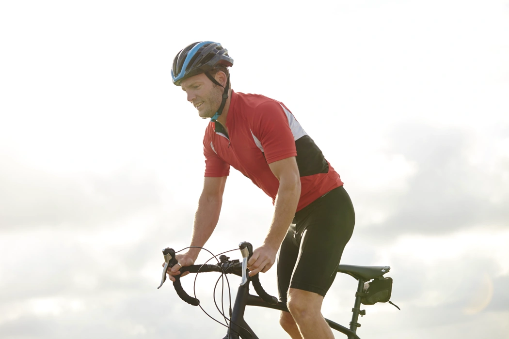 Cycliste sur route en position de pédalage, illustrant l’impact de la hauteur de selle, de l’inclinaison et de la posture sur le confort.