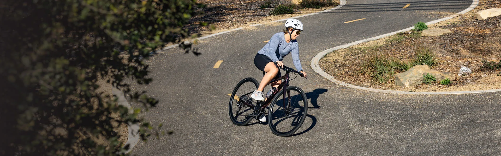 Cycliste sur route en virage, illustrant le lien entre posture, appuis et répétition du mouvement à vélo.