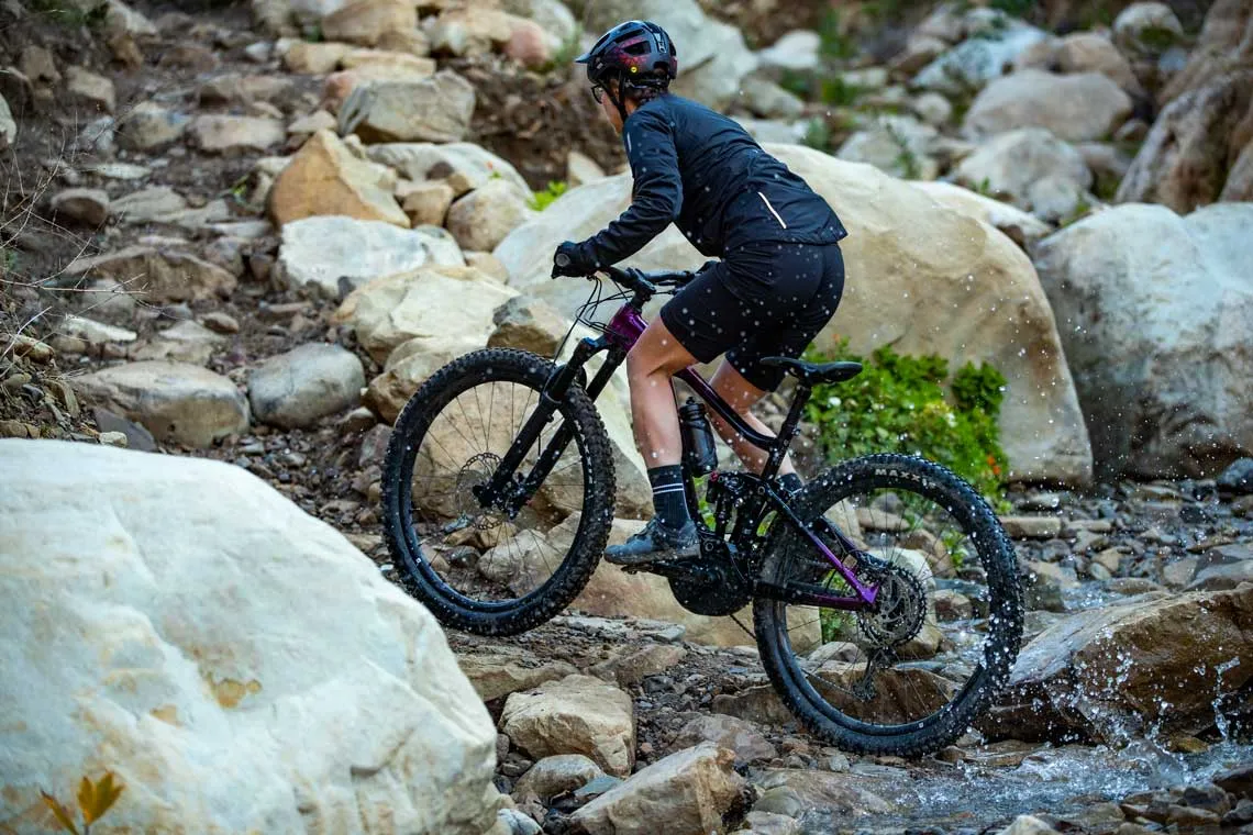 Cycliste en vélo de montagne sur terrain rocheux, illustrant comment retrouver un pédalage efficace avec de bons réglages.
