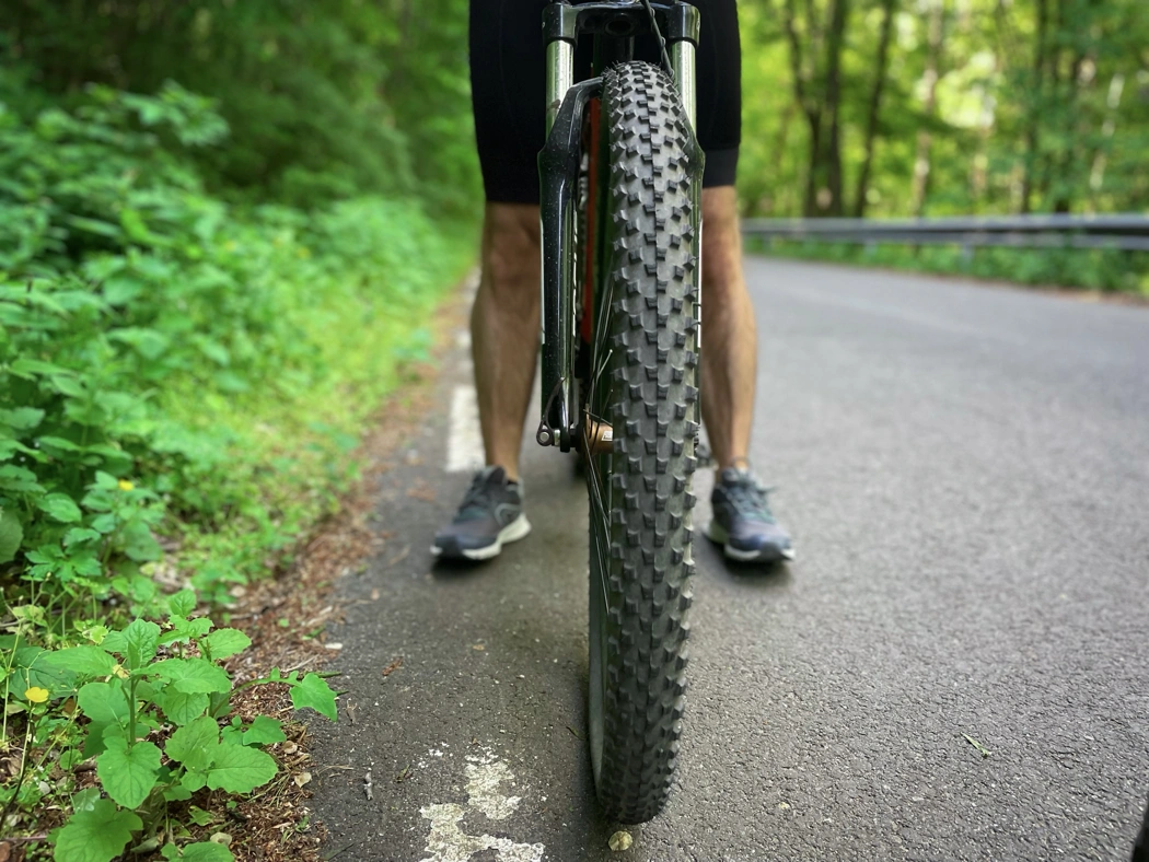 Pneu de vélo à crampons sur route asphaltée illustrant des pneus peu adaptés à un usage sur route.