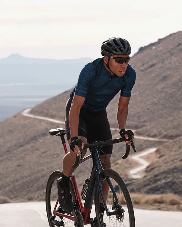 Cycliste sur route en montée illustrant la répartition du poids sur le vélo entre la selle, les pédales et le guidon.