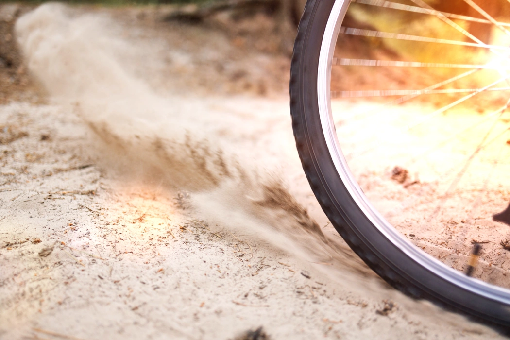 Roue de vélo roulant sur un chemin sablonneux pour illustrer l’effet de la pression des pneus sur la stabilité.