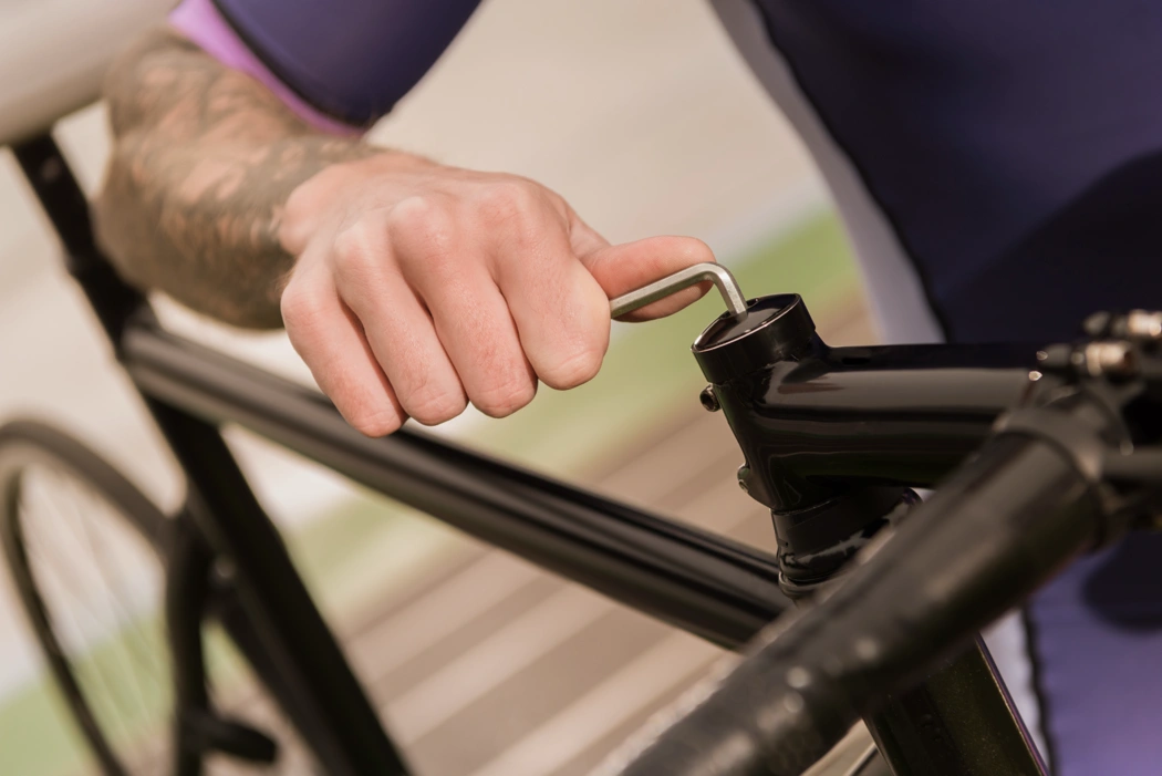 Ajustement du poste de pilotage d’un vélo avec une clé hexagonale pour améliorer la position et réduire le mal de dos.